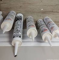 Five caulk tubes with nozzles visible