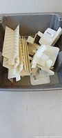 Bin containing assorted off-white plastic trim pieces
