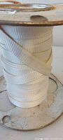 Flat white woven webbing on rusty metal spool