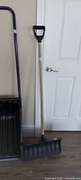 Snow shovel leaning beside door