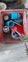 red plastic bin with blue couplings, PVC fittings, handle, compound tin, fasteners