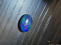 Top view of oval black opal showing multicolor play-of-color