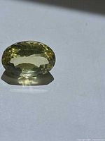 Faceted oval lemon citrine on flat surface showing table and pavilion reflections