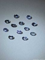 Group of 13 oval-cut tanzanite stones on neutral background