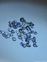 Group of small round and mixed-cut tanzanite stones spread on surface