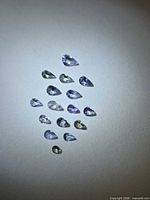 Array of 17 pear-cut Tanzanite stones on light background