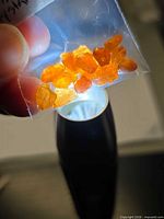 Bag of bright orange garnet crystals held to light