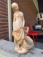 Full front view of concrete statue showing female figure and two basins