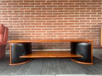 Front view of teak coffee table showing black curved ends and shelf