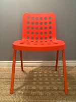 Front view of orange Pedrali chair showing perforated back and seat