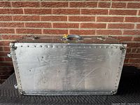 Front view of aluminum trunk showing riveted panel and latch hardware