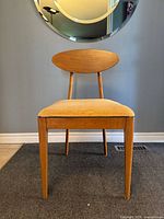 Front view showing oval backrest, upholstered seat and tapered legs