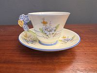 Side view of Paragon teacup on saucer showing floral design and blossom-shaped handle