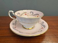Side view of teacup on saucer showing pattern and gold trim