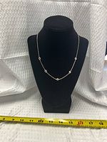 Necklace displayed on black bust with measuring tape showing length