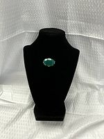 Front view on display showing green stone brooch