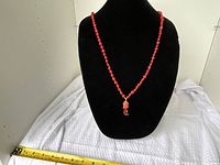 Front view of red beaded pendant necklace on display bust