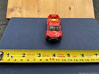Top view of red Hot Wheels car showing overall color, wear, tape for scale
