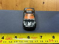 Top view of black Hot Wheels car showing orange roof insert and overall wear