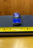 Front top view showing blue metallic color and overall size against measuring tape