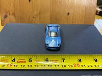 Top view of metallic blue Hot Wheels Ferrari F40 style car with ruler showing length ~3 inches