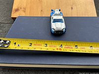Top view of the die-cast tow truck beside tape measure showing length