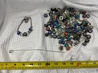 overview of bracelets and large group of loose charm beads with measuring tape for scale