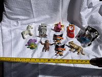 Group shot of all eleven toy figures with measuring tape for scale