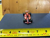 Front view of red Formula 1 toy car with ruler showing length