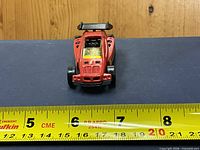 Front view showing red body, yellow windshield, black spoiler, paint wear, and length scale