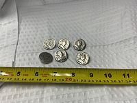 Front view of six coin motif buttons with tape for scale