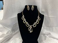 Necklace and earrings displayed on bust showing overall design