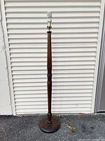 Full view of turned wood floor lamp on circular base