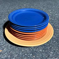 Stack of blue and orange Mainstays bowls on yellow Oneida plate