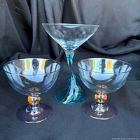 Front view of two iridescent coupes and one teal-stem martini glass