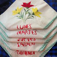 Stack of five napkins showing different floral embroidery and day names