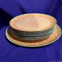 Stack of eight dinner plates atop platter showing pattern colors and rim design