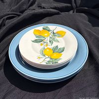 Stack of three blue dinner plates under four lemon salad plates