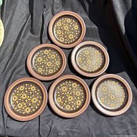 Five brown floral salad plates displayed on cloth backdrop
