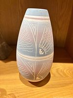 Front view of tapered pastel blue and mauve pottery vase with etched feather motifs