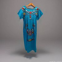 Full front view of turquoise hand-embroidered huipil dress on hanger