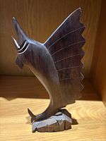 front view of carved wooden fish sculpture on base