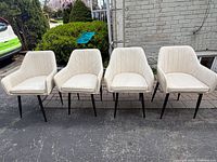 Front view of four cream leather chairs aligned side by side outdoors