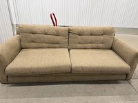 Full-size beige fabric sofa with button-tufted back cushions