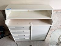 Front view showing four drawers, cabinet door, flip-top shelf