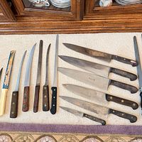 Group shot of 10 knives and honing steel on carpet