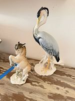 Front view of both porcelain figurines (horse and heron) on tabletop