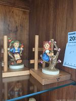 Both Hummel Apple Tree figurines on shelf