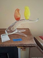 Full view of Murano glass sculpture showing two colored birds on clear branch with Murano sticker and measuring tape