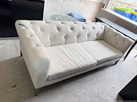 Full view of sofa front showing tufted back, seat cushions, legs